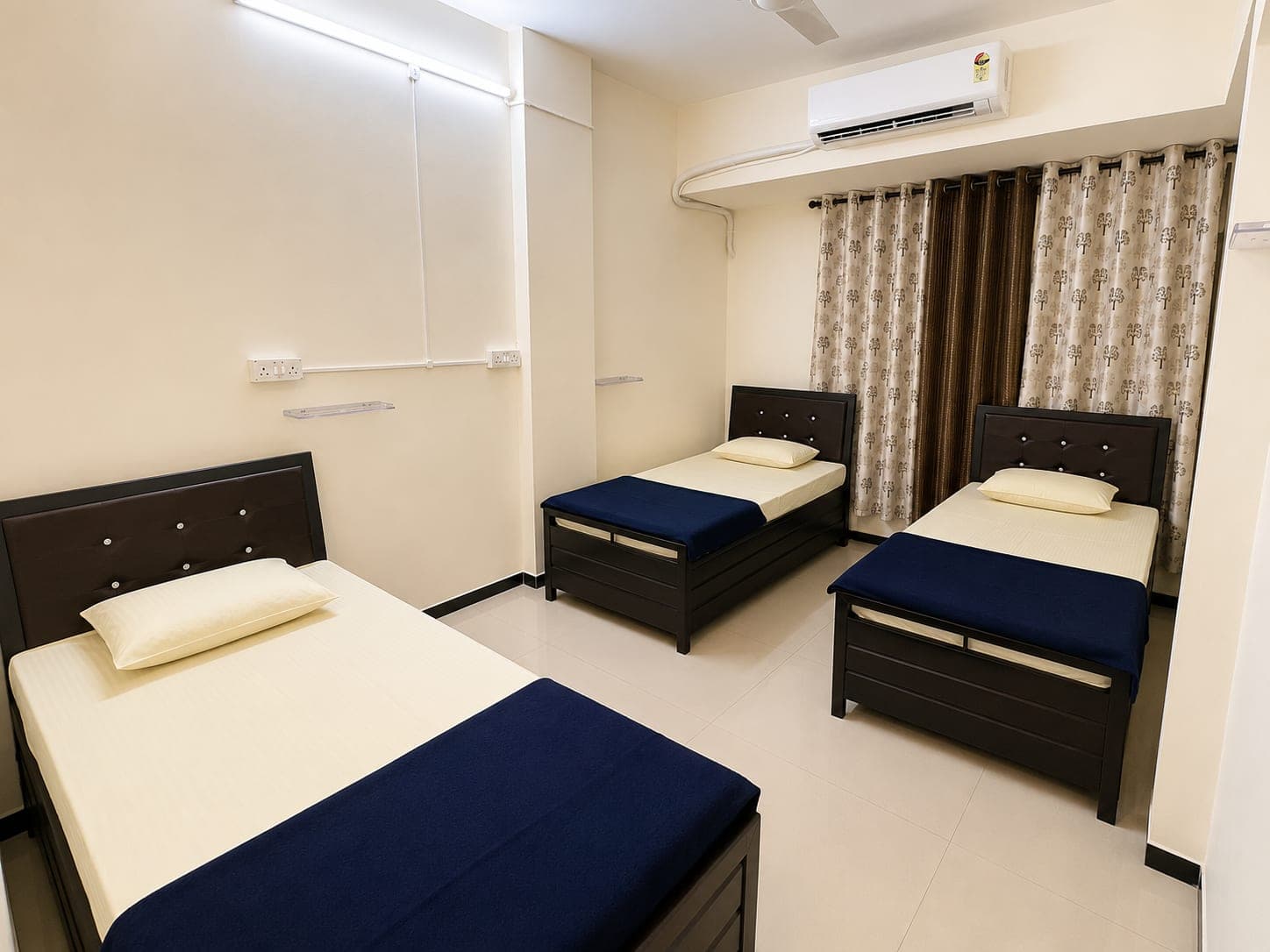 Three-sharing girls' room with AC, curtains and a plug point beside every bed