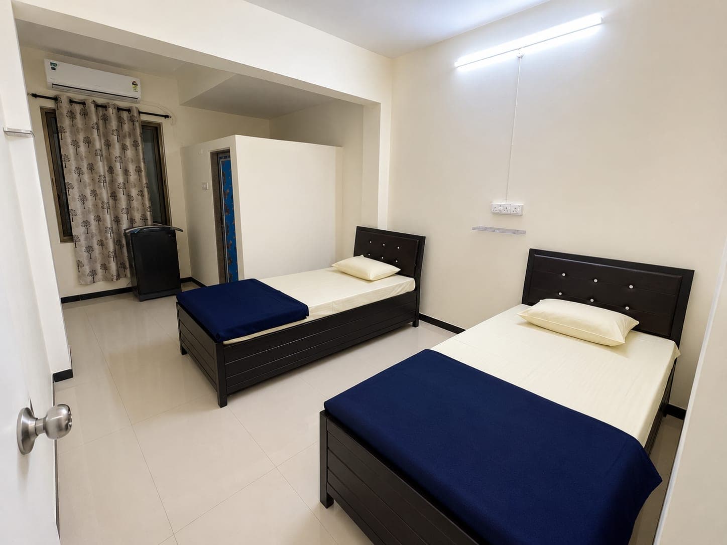 Two-sharing girls' room with single beds, storage under each bed and an air conditioner