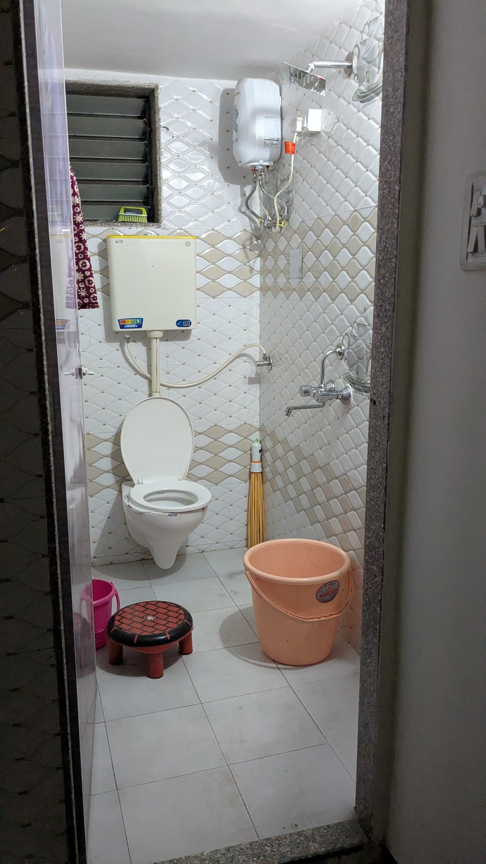 Tiled washroom with a geyser for 24×7 hot water at Om Shanti PG